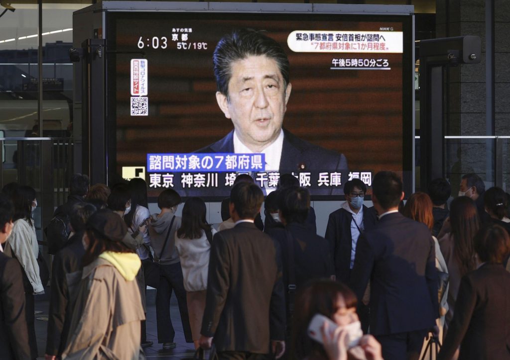 2020年4月6日月曜日、日本の大阪で日本の安倍晋三総理が総理官邸で演説する様子を映したテレビ画面を見る人々。安倍総理は、コロナウイルスの流行と闘う対策を強化するため、火曜日にも東京と他の6つの府県で緊急事態を宣言するものの、強硬な都市封鎖は行われないと語った。（共同通信、AP通信配信）