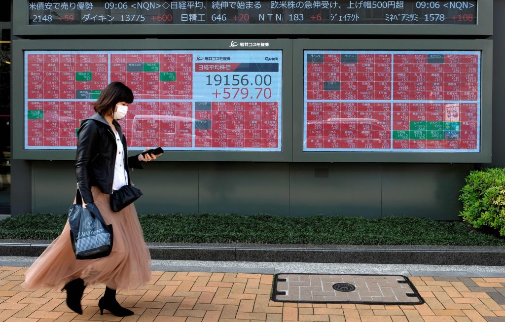 2020年4月7日、東京証券取引所の株価表示ボードの前を通る歩行者。（ファイル写真／AFP）