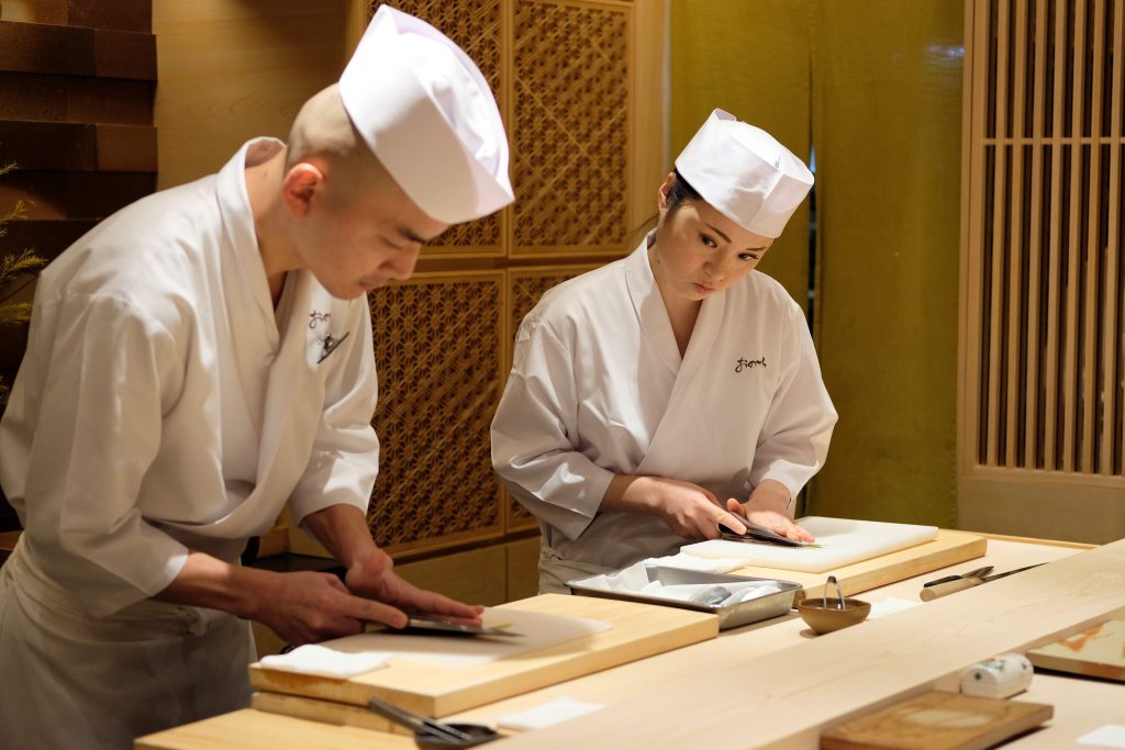 2019年11月27日撮影のこの写真で、東京の「鮨 銀座おのでら」で寿司の握り方を教わりながら魚の骨抜きをする同店の見習い、イワイミズホさん。女性は寿司職人になれないという考えを打ち砕こうと挑む日本の女性が増えており、日本でも最も尊敬を集める名店の数々で板前の修行を積み、働いている。（AFP）