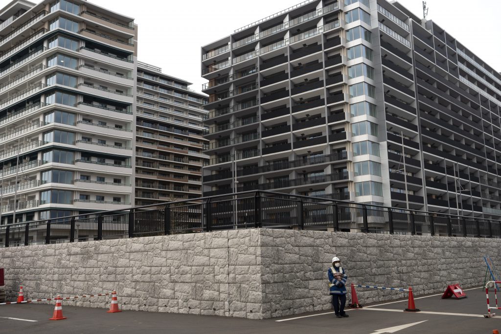2020年3月23日撮影の資料写真。2020年東京五輪の選手村に建つマンションの前に立つ警備員。ホームレスを代表する団体が、来年の東京五輪の選手村を新型コロナウイルスの感染拡大中の避難所として利用することを求めている。東京五輪の主催者と都に宛てたオンライン請願書には、東京湾沿いに建つ巨大な集合住宅を占有する許可を求める数万人の署名が集まった。（AP 写真）