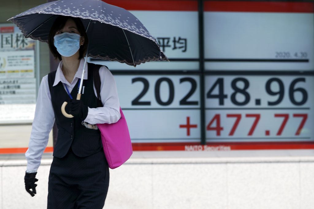 2020年4月30日木曜日、東京の証券会社の日経225指標を表示する電光掲示板を通り過ぎる女性。米国経済が2009年以来最悪の四半期業績を記録したことを示すデータがあるにもかかわらず、コロナウイルス治療薬の可能性をめぐる楽観的な観測から、ウォール街ではそのデータを打ち消すのに十分な急反発が起こった波に乗り、木曜日にアジアの株価は上昇した。(AP写真)