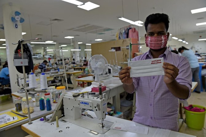 コロナウイルス感染症パンデミックの中、企業家ヌール・カムダン氏（写真には入っていない）がデザインした保護マスクを見せるバングラデシュ人労働者のフセイン・ナズムル氏（マナーマの東、バーレーン北部にあるアブ・サイバ村の工場にて）。4月25日（AFP）