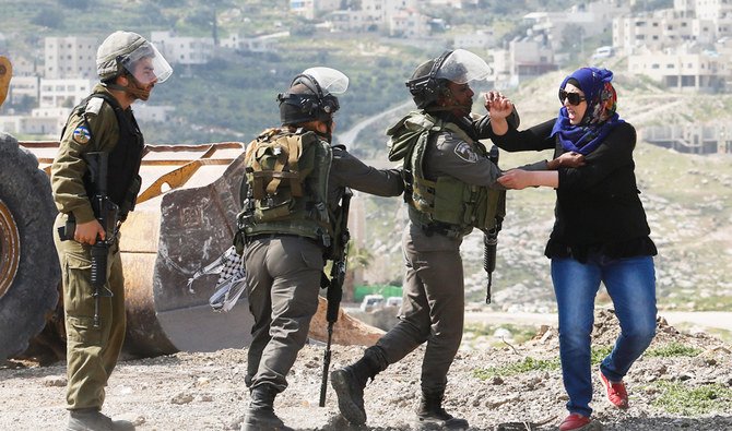 ユダヤ人入植地としてイスラエルが土地を押収したと主張するパレスチナ人の抗議活動を排除するイスラエル国境警備隊と取っ組み合いになるパレスチナ人女性、ヨルダン川西岸地区、アブ・ディス付近、2015年3月17日火曜日。（AP）