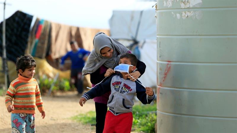 レバノン南部でコロナウイルスの感染拡大の予防策として、男の子の顔にマスクをつけるシリア難民。（ロイター通信）