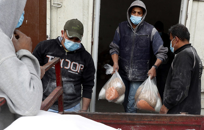 ガザ市シェイクレッドワン地区にて、貧しい難民の家族のために国連救援・労働局（UNRWA）から配給された食料の荷下ろしをするパレスチナ人労働者。（AP)