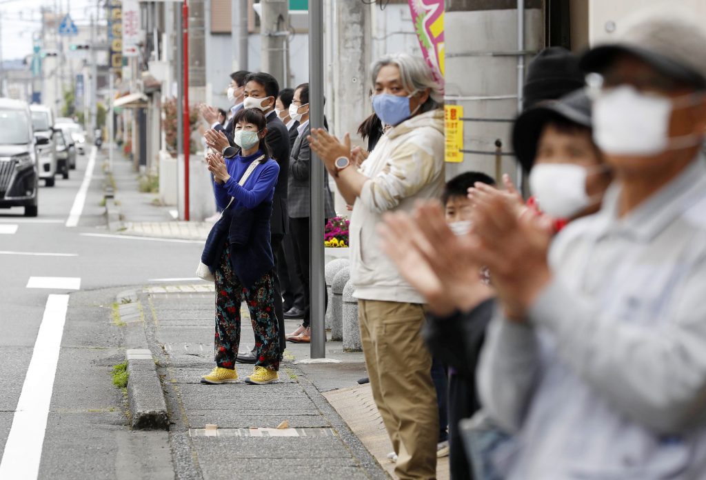 2020年5月1日撮影。新型コロナウイルスの世界的流行を受け、全国で非常事態宣言が発令される中、日本の中部、静岡県裾野市で新型コロナと闘う医療従事者への感謝の気持ちを示すために拍手する人々。日本では、このウイルスは感染症の流行だけではなく、感染者や医療従事者、必要不可欠な仕事をしている人たちに対する激しいいじめや差別をもたらした。（喜多信司/共同通信 AP経由）