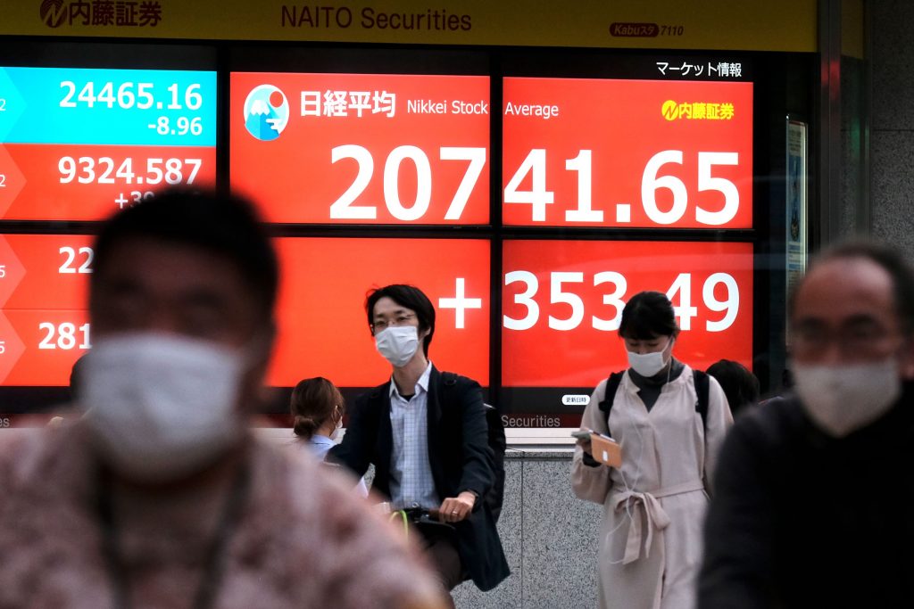 東京証券取引所の株価を表示している電子株価ボードの前を歩く歩行者たち。2020年5月25日、東京。（資料写真/AFP）