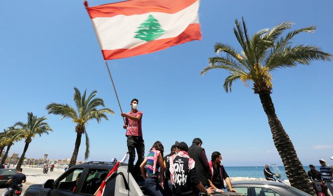 高まる経済的苦境に対する抗議活動中に、新型コロナウイルス感染症の予防のためにマスクを着用し、レバノン国旗を振るデモ参加者。ティルスにて。 （ロイター/資料）