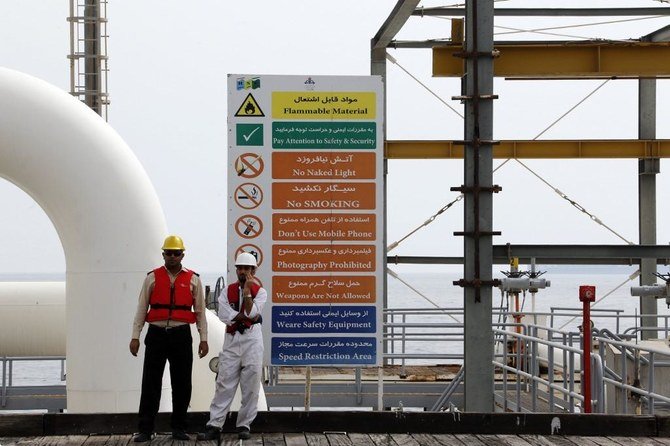 上部、ハールク島の石油施設で安全指示が表示された標識の側に立つイランの労働者。（AFP記録写真）