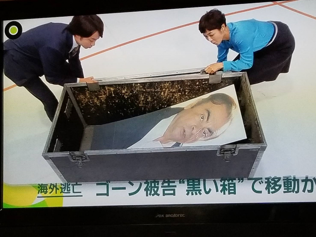 日本の地元のテレビネットワークのプレゼンターとニュースキャストは、国境検査官を逃れるためにゴーンが使用したものと同様の正確な大きさのモックボックスを示しています。(Supplied)