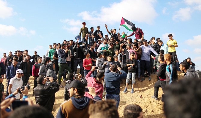 2018年3月30日、ガザ市の東のイスラエル国境近くで、土地の日を記念するデモで国旗を振るパレスチナの抗議者たち。（AFP）