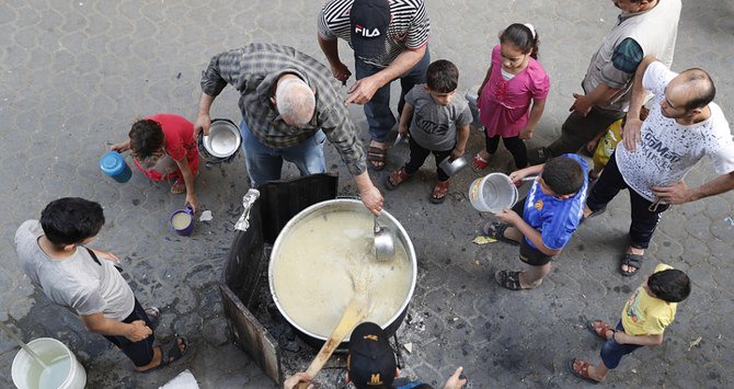 ガザ市で朝食を取る前の貧しい住民に、パレスチナ人が暖かい小麦のスープとポリッジを配っている。（AP通信）