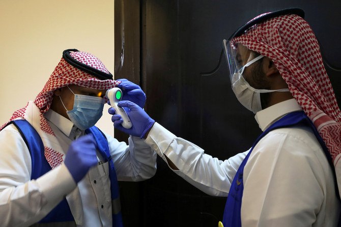 2020年5月10日、サウジアラビアのリヤドで、コロナウィルス（COVID-19）の感染拡大に続く神聖なラマダン月間に、保護マスクと手袋をしたサウジアラビア人のボランティア監督者が、慈善団体から提供されたイフタール料理の箱の準備を開始する前に、別のボランティア員の体温を測る。（ロイター）