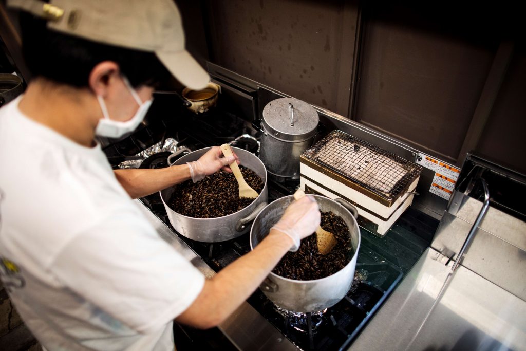 東京のキッチンで篠原祐太氏がコオロギを揚げている。自宅調理用のコオロギラーメンの素材の一部として使う。2020年5月13日撮影。（AFP）