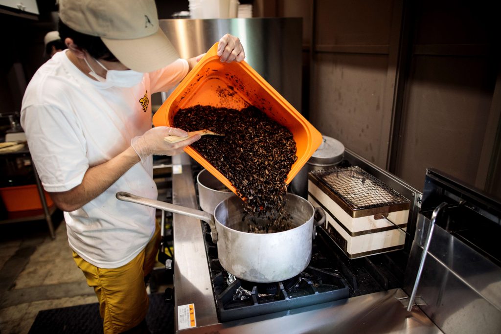東京のキッチンで篠原祐太氏が乾燥コオロギを調理している。自宅調理用のコオロギラーメンの素材の一部として使う。2020年5月13日撮影。（AFP）