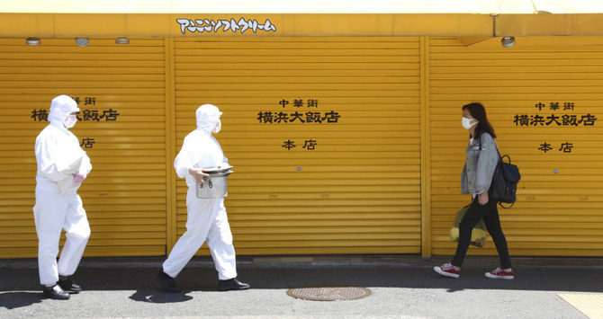 新型コロナウイルス感染拡大に備え防護服を着用して横浜中華街を歩くレストラン従業員ら。2020年5月8日金曜。（AP）
