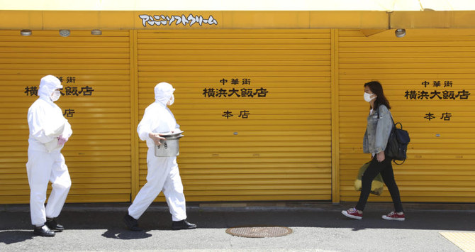 新型コロナウイルス感染拡大に備え防護服を着用して横浜中華街を歩くレストラン従業員ら。2020年5月8日金曜。(AP)