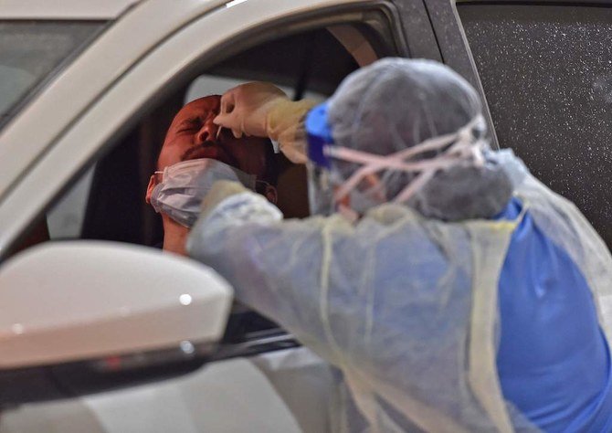 COVID-19 のパンデミックの中、2020年5月7日にサウジアラビアの首都リヤドのディリヤ病院にて、ドライブスルーによるコロナウィルステストキャンペーンが行われ、保健担当員たちが鼻腔に綿棒を入れて検査を行う。（AFP）