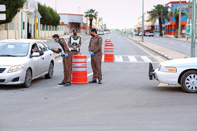 水曜日、サウジ北西部のジャウフ州タバルハルの道路で、自動車ドライバーのチェックを行う外出禁止令執行中の警察官。(SPA)