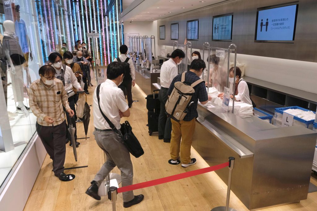 2020年6月19日、東京銀座のショッピング街のユニクロ店舗で、日本のファーストリテーリング社製マスクを買物客たち（左）が購入している。（AFP通信）