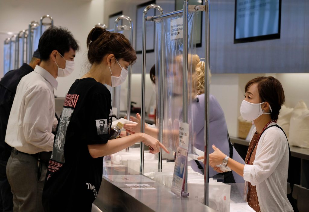 2020年6月19日、東京銀座のショッピング街のユニクロ店舗で、日本のファーストリテーリング社製マスクを買物客たち（左）が購入している。（AFP通信）
