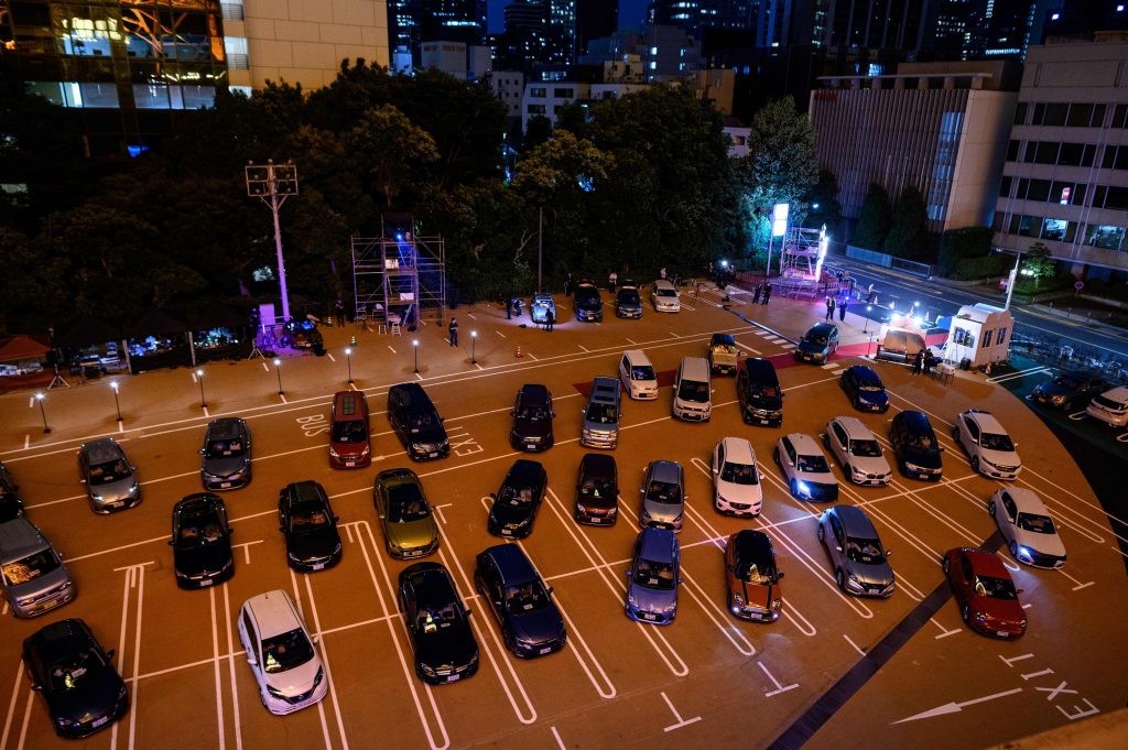 東京で行われたドライブインシアター・イベントへ車に乗ったまま参加する人々の駐車場に駐めた車。このイベントはCOVID-19コロナウィルス・パンデミックにより社会的制約が課せられる中の2020年6月20日に東京タワーの真下で開催された。（AFP）