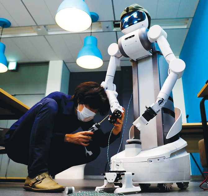 Mira RoboticsのCEOである松井健氏が、会社研究所でのデモで、人型ロボットのugoを自ら操作。同社従業員がugoの調整を行う。（ロイター）