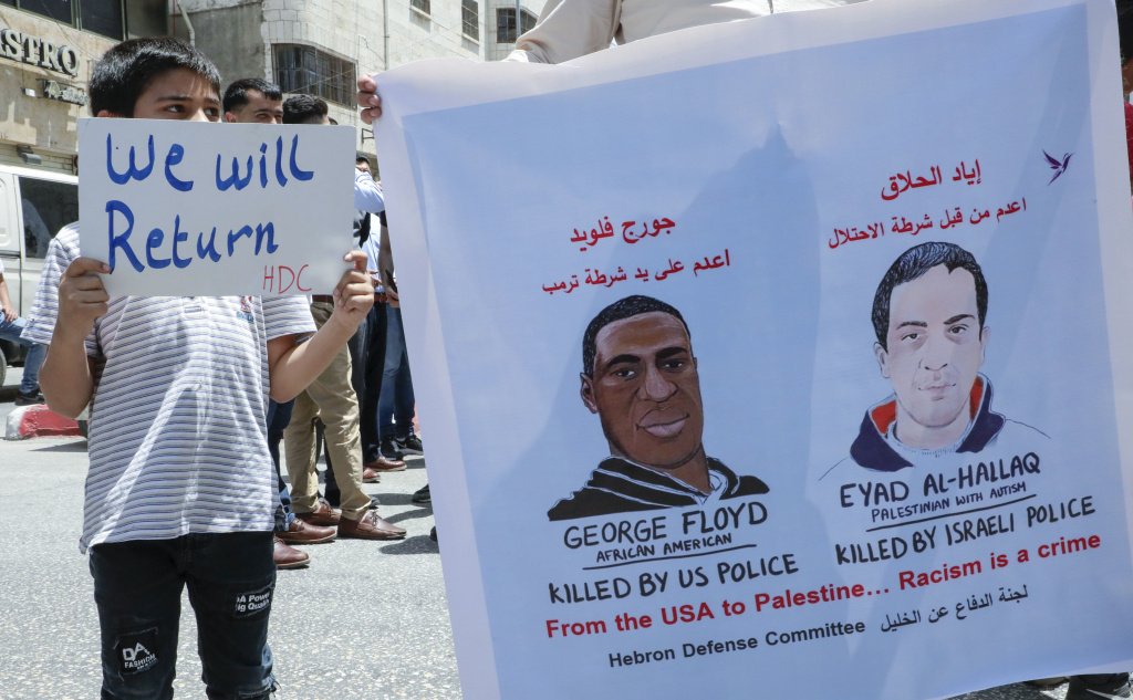 ヨルダン川西岸のヘブロン市でイヤド・ハラクさんとジョージ・フロイドさんの殺害に抗議するパレスチナ人たち。（AFP通信）