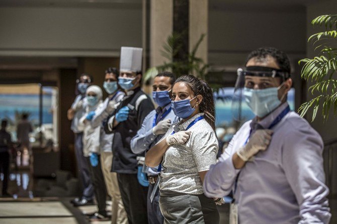 マスクやフェイスシールド、ゴム手袋を装着して一列に並ぶヒルトン ハルガダ プラザの従業員。エジプト南部にある紅海県の都市ハルガダから来た客を迎え入れていた。2020年6月19日撮影（AFP）