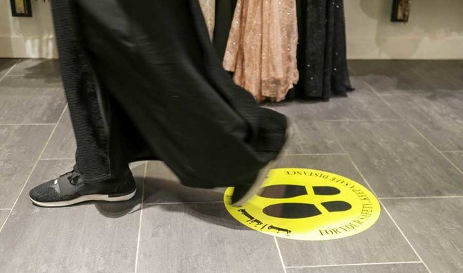 新型コロナウイルス感染症の拡大防止策として、ショッピングセンターで社会的距離を示すマークの上を歩くサウジアラビアの女性。2020年5月3日、サウジアラビア、リヤド。（ロイター）
