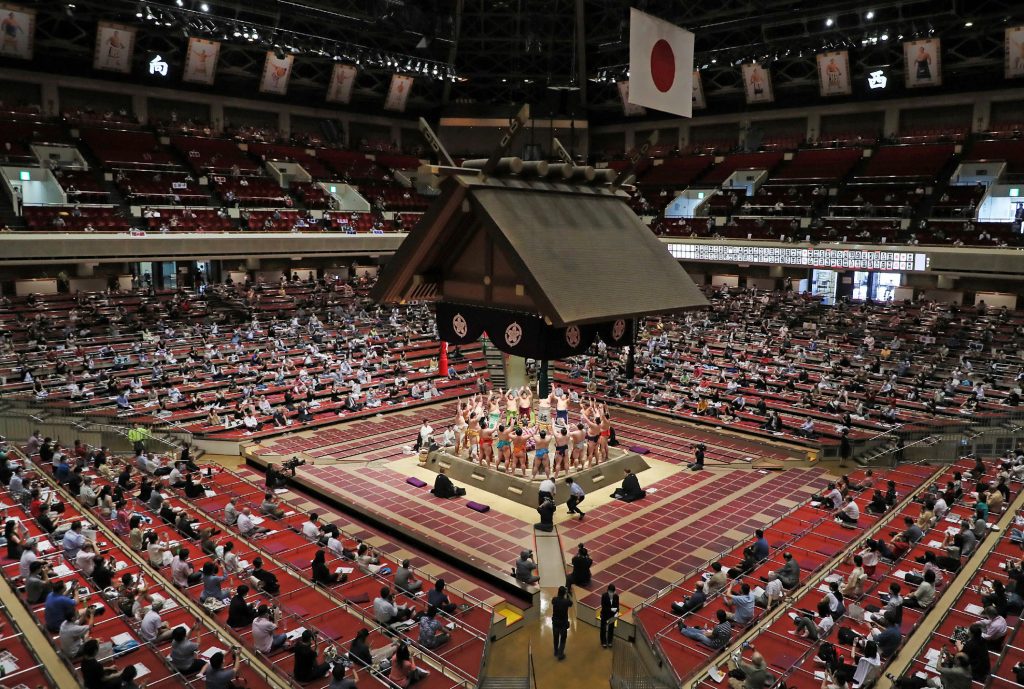 2020年7月19日、東京の主要開催場所である両国国技館での2週間の大相撲場所の取組前の儀式を観る間、観客たちはソーシャルディスタンスを守り、離れて座っている。(AFP)