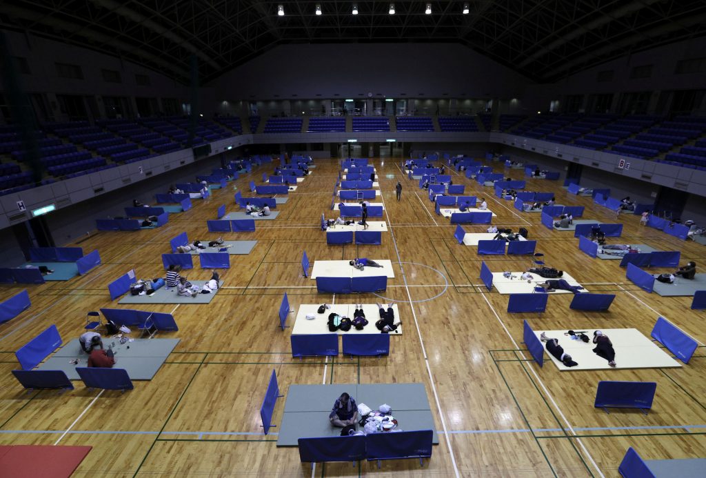 2020年7月7日、日本南西部の熊本県で豪雨による洪水や土砂崩れが発生した後、八代市の体育館で、人々が新型コロナウイルス感染拡大によるソーシャルディスタンスを維持すべく段ボールを使って一時避難所で休憩する。（資料写真/ロイター）