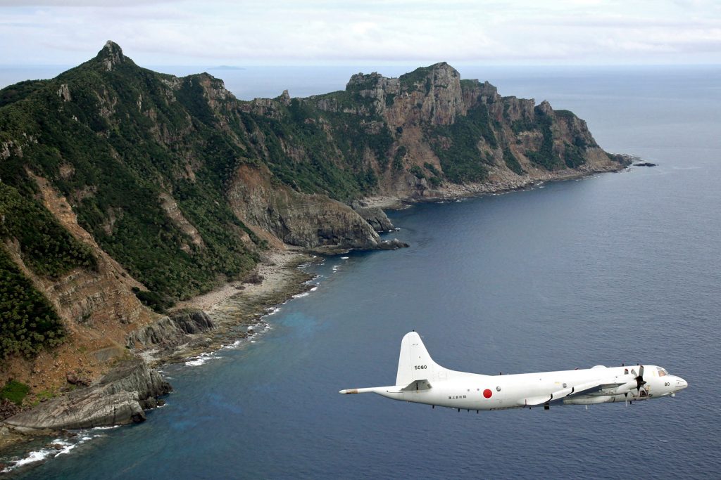 日本の海上自衛隊に属するP-3C オライオン哨戒機が、東シナ海で問題となっている島（日本では尖閣諸島、中国では釣魚島）の上空を飛行している。（AP通信経由の写真/共同通信）