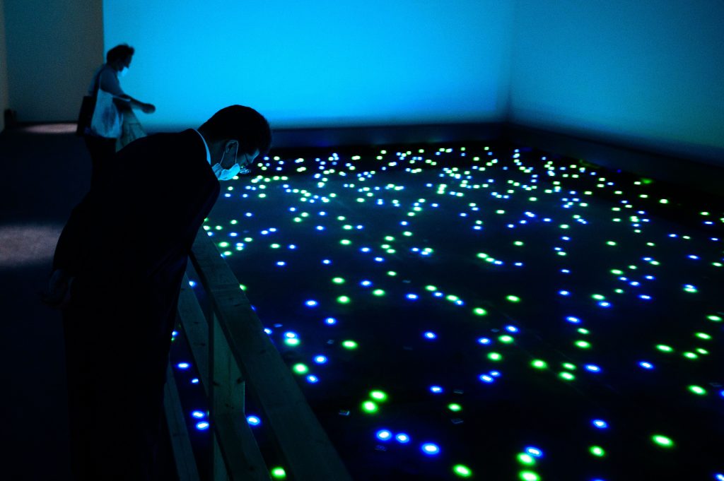 東京の森美術館で開催された「STARS展:現代美術のスターたち― 日本から世界へ」のプレス向け内覧会で、宮島達男の『時の海─東北』プロジェクトをマスクを着けて鑑賞する観客。2020年7月30日に撮影。(AFP)