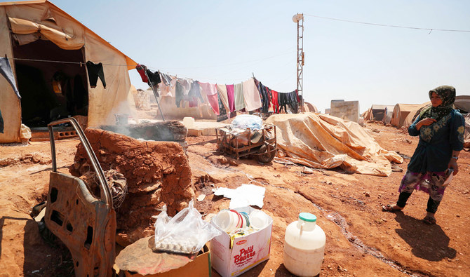 2020年7月11日、シリア北西部のイドリブ県マーラトミスリンの近く、イドリブ県とアレッポ県のシリア難民キャンプで、テントの隣に立つシリア人女性。（AFP）