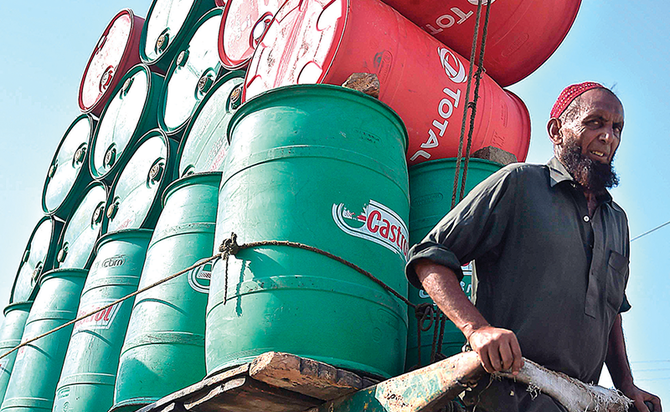 空の石油ドラム缶を載せた荷車を引くインド人労働者。OPECとロシア主導の産油同盟国は石油生産高を5月以降1,000万BPD減少させている。（AFP）