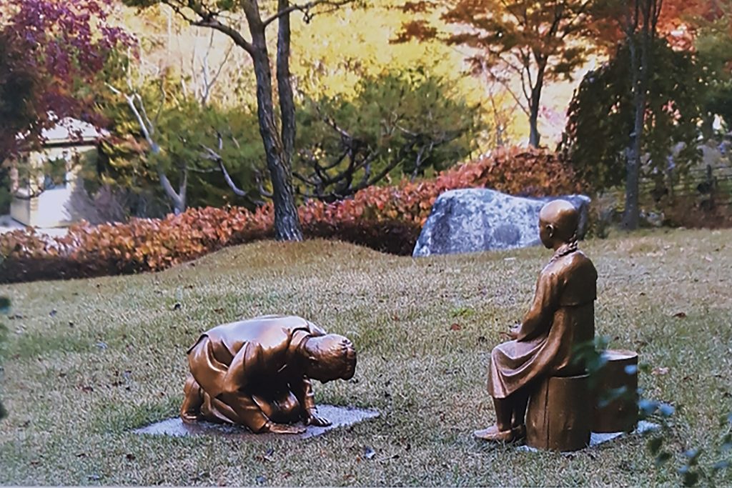 韓国平昌の植物園に設置された少女像の前にひざまづく男性像。少女像は第二次世界大戦中の旧日本軍による性奴隷被害者を象徴する。日韓両国の外交の機微に触れる問題として浮上しつつある。（資料写真/韓国植物園、AP通信）