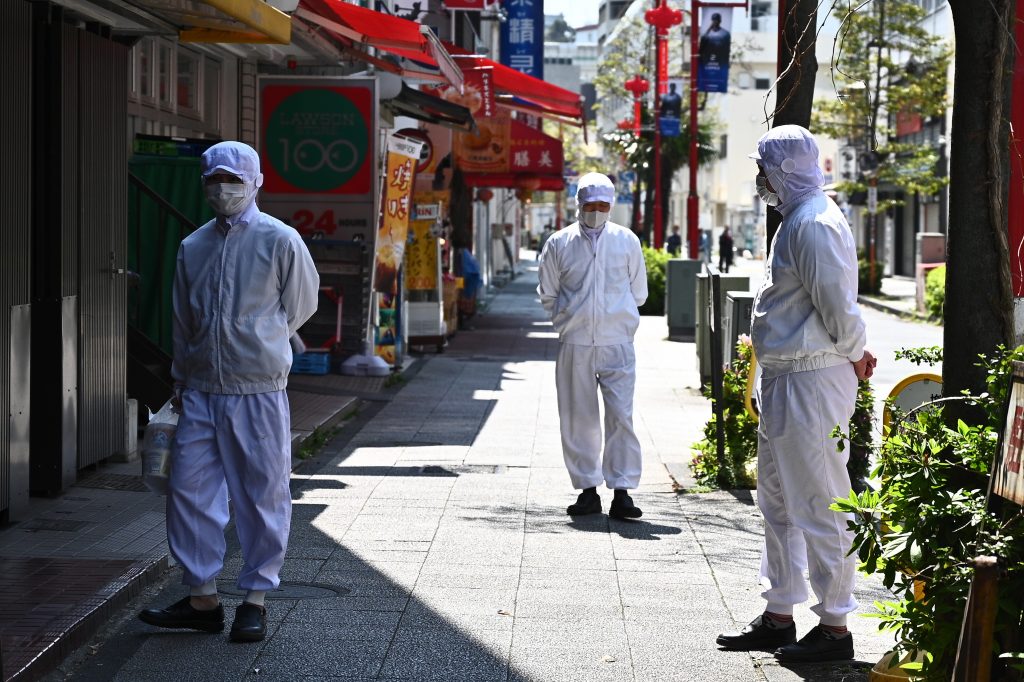 2020年4月9日に横浜中華街で、マスクを着用した従業員が開店前に店先に立っている。（AFP）