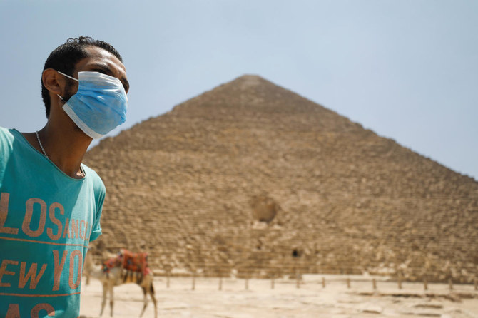 エジプト・カイロで2020年7月1日、コロナウイルス感染症（COVID-19）の発生後、観光客の訪問を再開したギザの大ピラミッドの前で、フェイスマスクをつけた男性の姿が見られる。（ロイター）