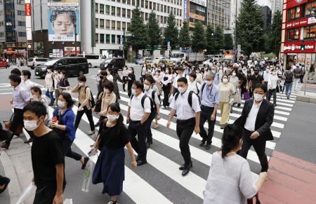 新しいコロナウイルスの広がりを抑制するためにフェイスマスクを着用した人々は、水曜日に東京の通りを歩きます。(AP経由の共同通信)