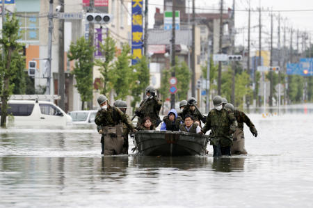 日本南部の福岡県大牟田市で豪雨により道路が冠水し、住民をボートで救出する自衛隊員。救助活動は続いており、雨の被害は九州本島でより広域に及んでいる。（AP）