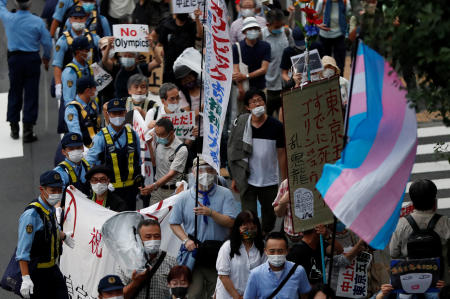 金曜、東京の国立競技場近くで東京2020オリンピックに反対する看板を掲げるマスク姿のデモ参加者たち。(ロイター)