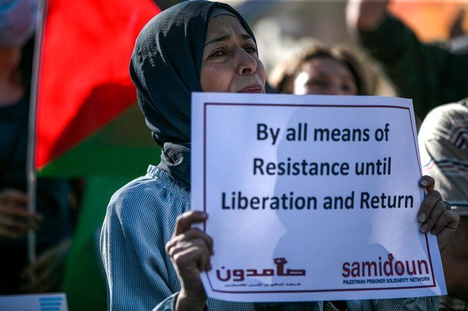 2020年7月1日、ヨルダン川西岸の都市ラマッラの中心部で、西岸の占領地区の一部を併合するというイスラエルの計画に反対するデモが起こり、その最中に抗議者が看板を持って立っている。（AFP通信）