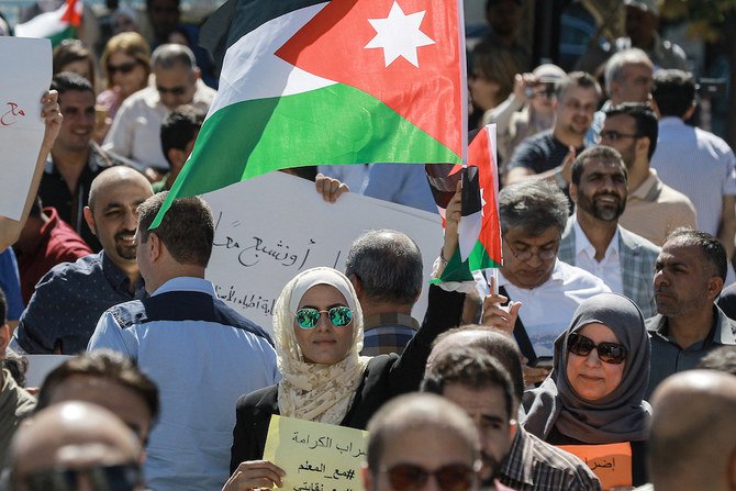 2019年10月3日にヨルダンの首都アンマンにあるプロフェッショナル・アソシエーション・コンプレックスで、公立学校の教員たちがデモを開催し、昇給を要求するなか、ある女性がヨルダンの国旗を掲げて立っている。（資料／AFP通信）