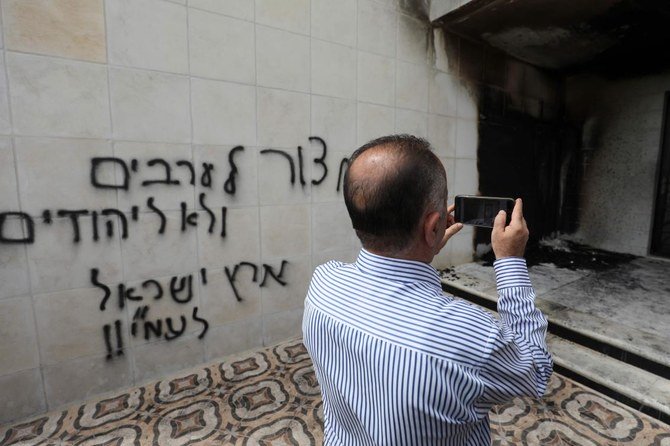 放火され、ヘブライ語で落書きを吹きかけられたモスクの入り口で被害状況を点検するパレスチナ人（AFP）