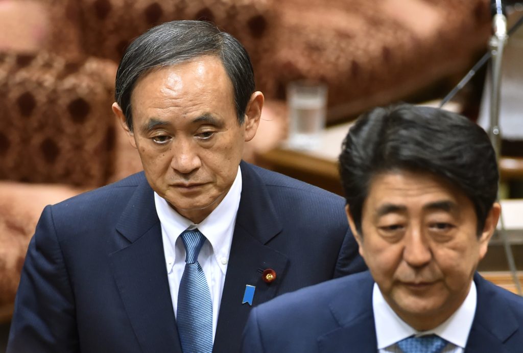 2016年5月13日、東京の衆議院予算委員会を去る日本の菅官房長官（左）と安倍晋三首相（右）（AFP）