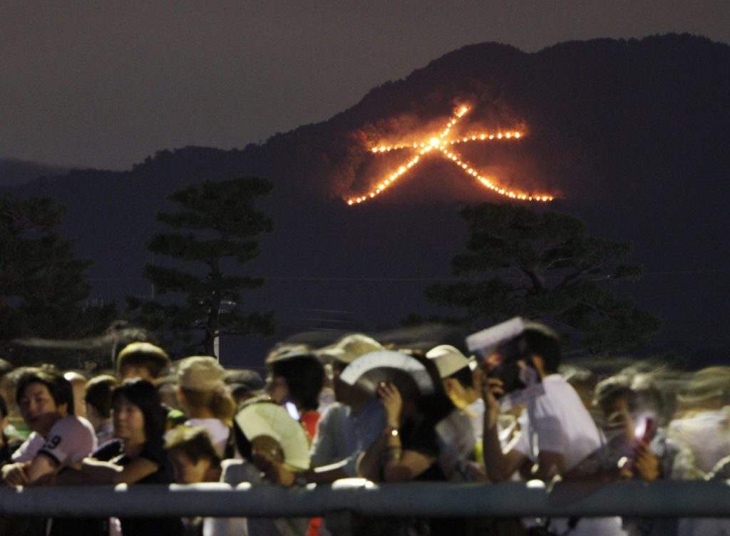 午後８時、東山の如意ケ嶽に点火され、巨大な「大」の字が夏の空に浮かび上がると、見物客から歓声が上がった。(AFP)