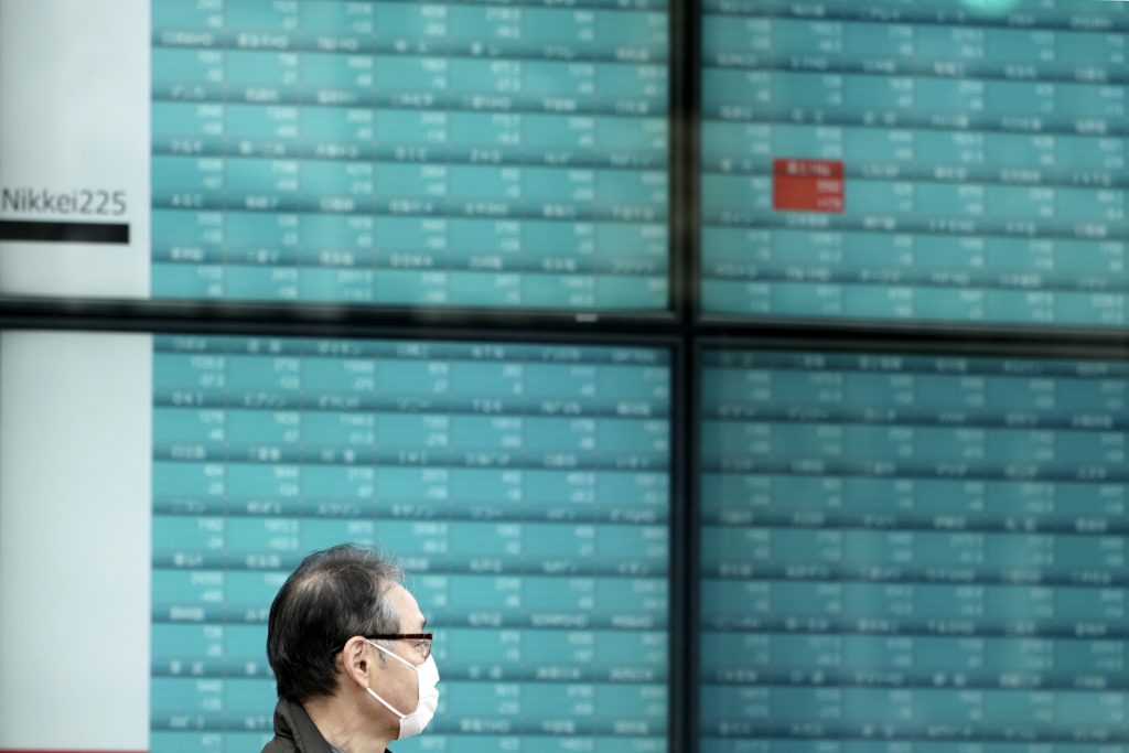 東京の証券会社で、日本の日経225指数を示す電子掲示板の前を通り過ぎる男性。2020年2月25日撮影。ドナルド・トランプ大統領が新型コロナウイルスのパンデミックの影響を受けた米国民に対し減税や失業保険給付の上乗せを提供する大統領令を発令後の2020年8月10日(月)、アジア株の大方が上昇した。(AP写真/ Eugene Hoshiko)