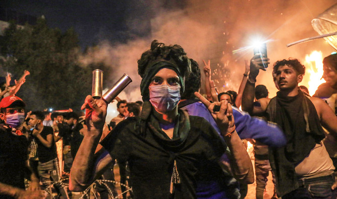 カルバラーの反政府抗議集会でデモ参加者の1人が催涙ガス弾を指にはめてVサインを示している。（AFP）