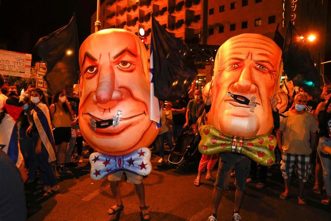 ベンヤミン・ネタニヤフ首相（左）とベニー・ガンツ副首相（右）のマスクをかぶったイスラエルのデモ隊が2020年8月22日、エルサレムの首相公邸前で行われた反政府デモに参加した。（AFP）